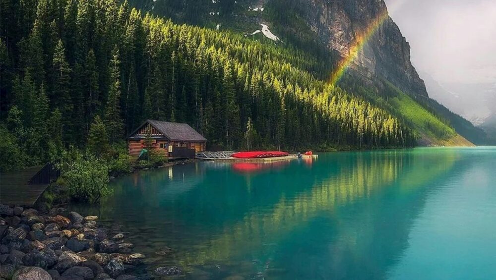 a rainbow shines in the sky over a mountain lake